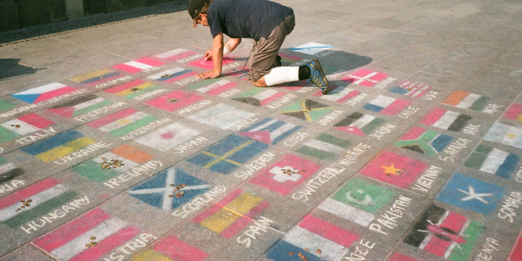 Street artist drawing flags of the world in chalk