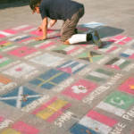 Street artist drawing flags of the world in chalk