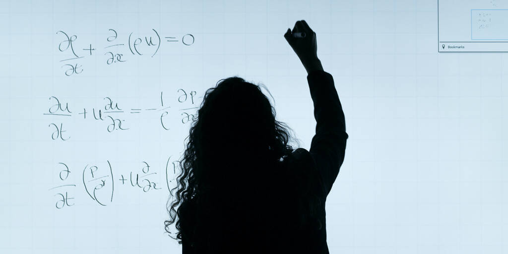 Woman with long wavy hair writing on a white board