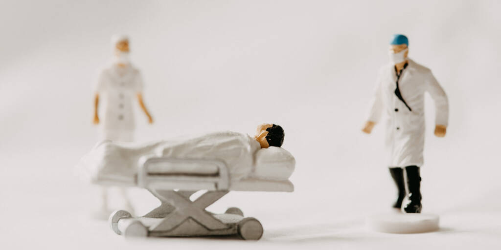 miniature figures in hospital clothing with patient in a bed